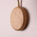 Wooden circular device with a cable on a pink background