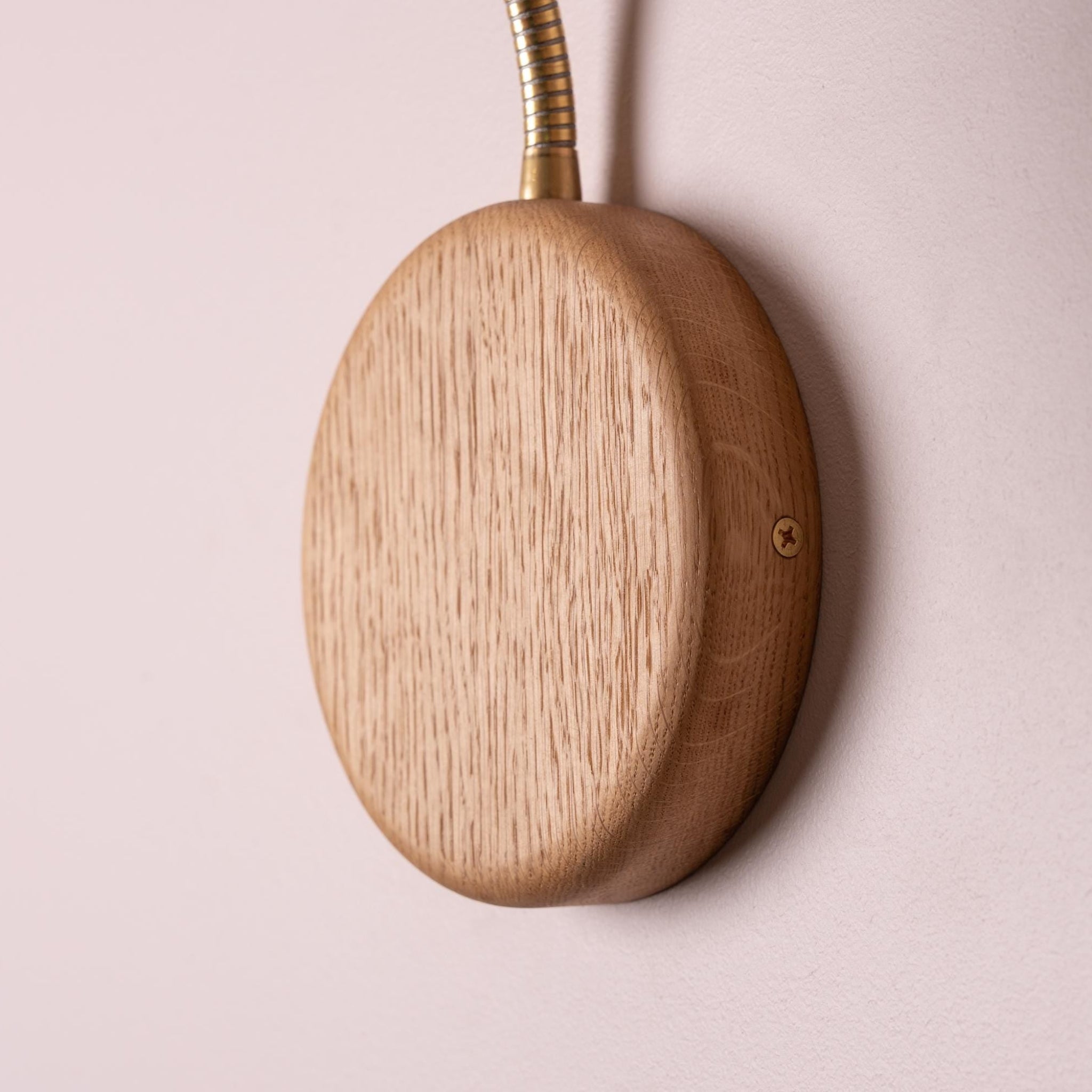 Wooden circular device with a cable on a pink background