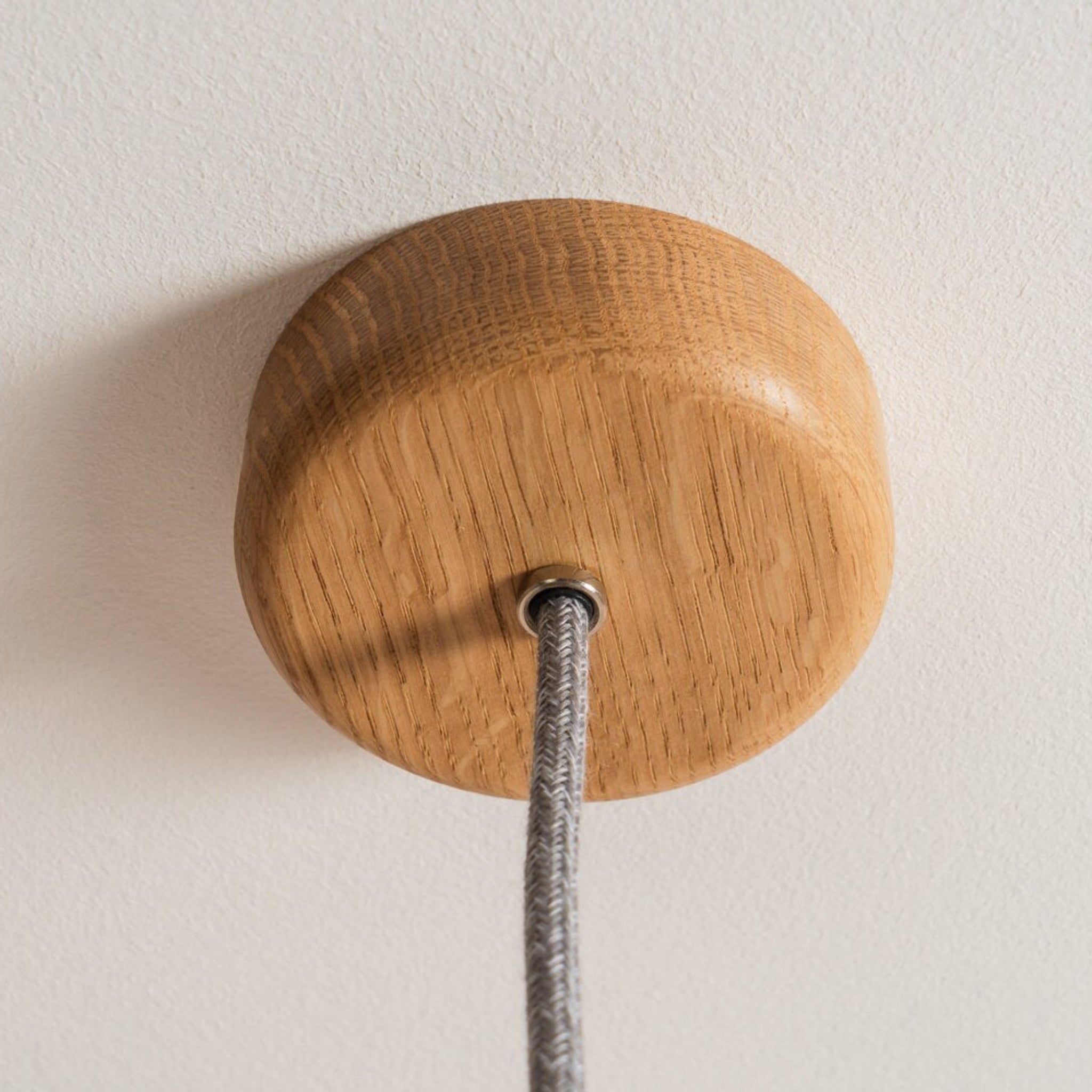 Wooden ceiling rose with a cable on a plain background