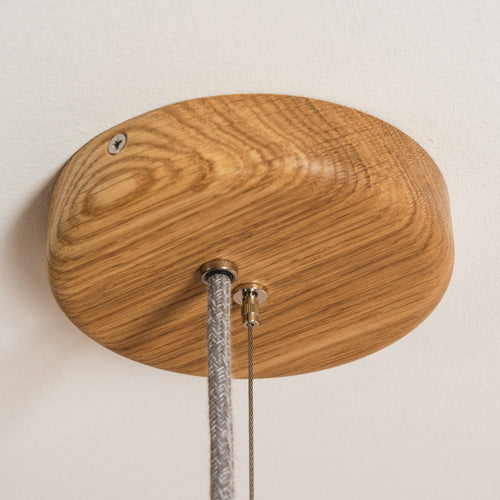 Wooden ceiling rose with cable on a plain wall