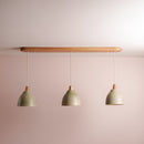 Three ceramic pendant lights with oak wooden fixtures and green ceramic shades on a plain wall.