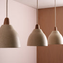 Three pendant lights with a speckled cream ceramic shade with oak caps in front of a wooden wall