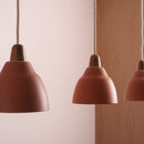 Close up of three pendant terracotta lights with wooden end caps.
