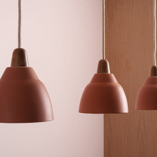Close up of three pendant terracotta lights with wooden end caps.