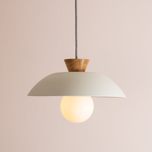 Side view of white ceramic pendant light with round bulb and oak end cap